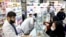 Pharmacists talk with customers at a drugstore in downtown Tehran, February 25, 2020