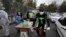 A biker wearing a face mask to curb the spread of the new coronavirus drives past a group of people selling hand sanitizer at a low price in Tajrish square in northern Tehran, April 16, 2020