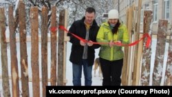 Former regional lawmaker Arkady Vasilyev and union leader Ulyana Mikhailova ceremonially open a fence at a Pskov school that is meant to protect students from a terrorist attack. 