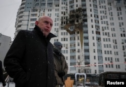 Ministrul britanic al apărării, John Healey, în vizită la Kiev, 9 ianuarie 2026, în fața unei clădiri lovite de o dronă rusă.