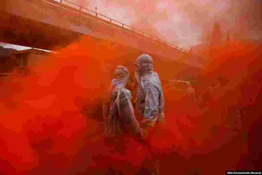 Two revelers are seen amid flare smoke as they celebrate &quot;Ash Monday&quot; on February 19 by participating in a colorful &quot;flour war,&quot; a traditional festivity marking the start of the 40-day Lent period until Orthodox Easter. (Reuters/Alkis Konstantinidis)