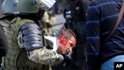 Riot police violently detain a protester during an opposition rally in Minsk against the election results.