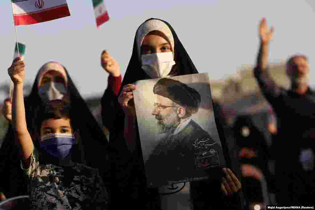 A supporter of Ebrahim Raisi displays his portrait during a rally in Tehran to celebrate his Iranian presidential election victory.