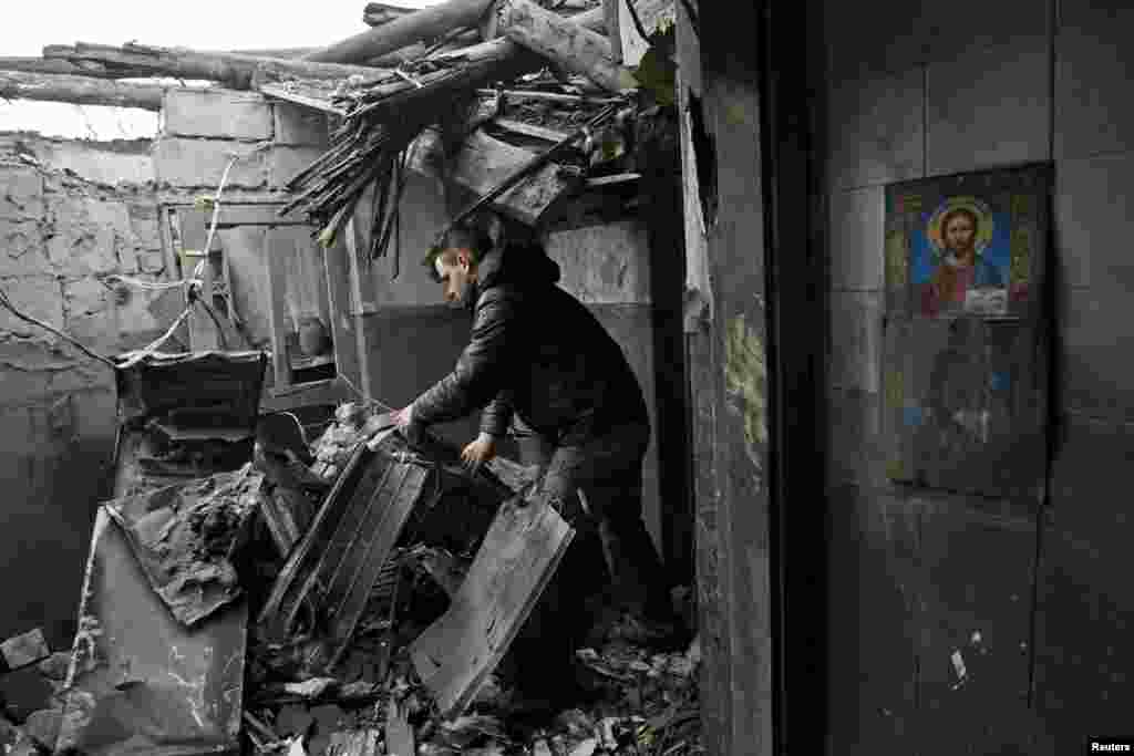 A local resident inspects debris inside his damaged home that locals say was caused by recent shelling in Makiivka, a town controlled by separatist forces in Ukraine's Donetsk region on March 24. (Reuters/Alexander Ermochenko)