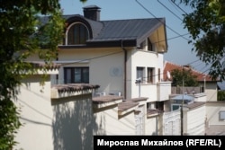  Зад оградата има две къщи, а на фасадата на едната от тях има глава на лъв. 