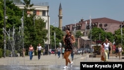 Një grua e re duke ecur pranë një shatërvani gjatë një dite të nxehtë vere në Prishtinë. Fotografi nga arkivi.