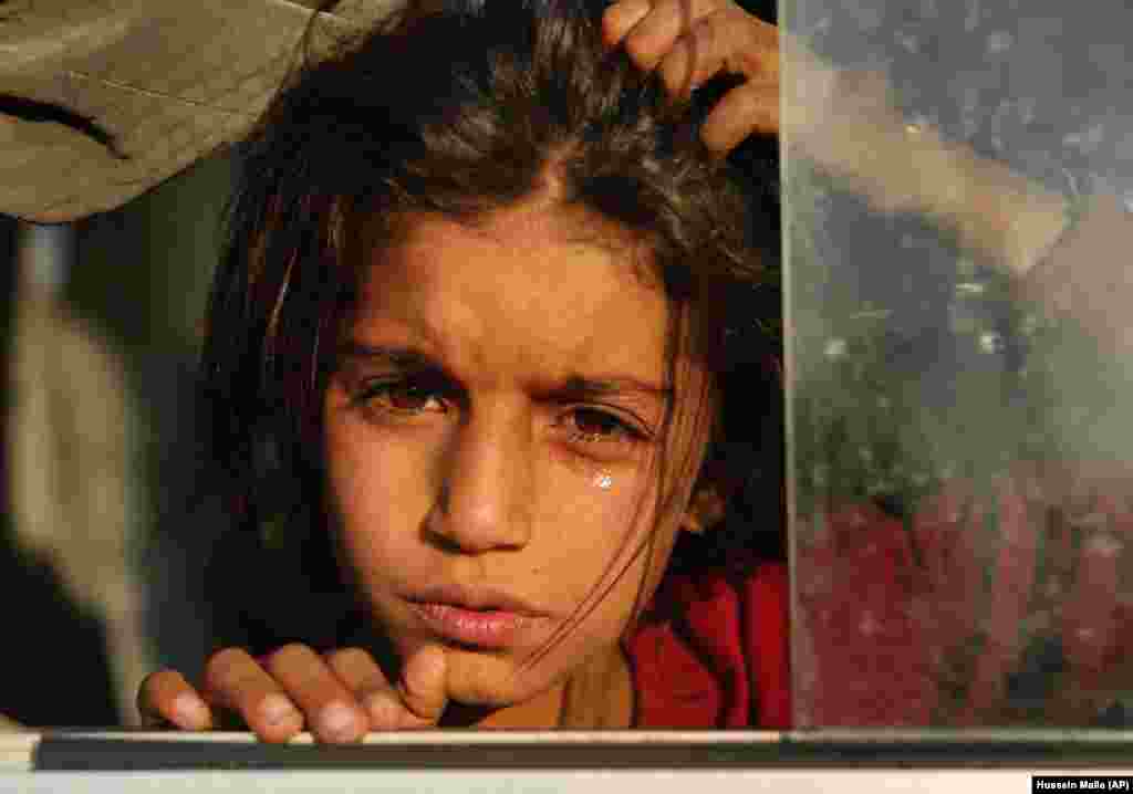 A girl newly displaced by a Turkish military operation in northeastern Syria weeps as she sits in a bus upon her arrival at the Bardarash camp, north of Mosul, Iraq. (AP/Hussein Malla)