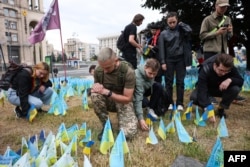 Soldiers and activists place Ukrainian flags with an LGBT coat of arms in tribute to fallen LGBT soldiers at a makeshift memorial on Independence Square on June 16.