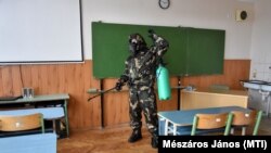 Katona fertőtleníti a szolnoki Kassai Úti Magyar-Angol Két Tanítási Nyelvű Általános Iskola egyik tantermét 2020. október 26-án 
