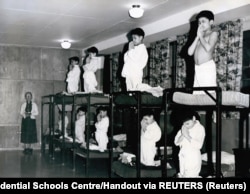 Câțiva băieți se roagă pe paturi suprapuse într-un dormitor de la Bishop Horden Memorial School, o școală rezidențială din comunitatea indigenă Cree din Moose Factory, Ontario, Canada, în 1950.