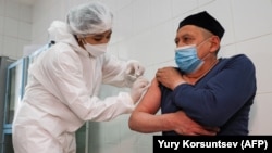 Медицина қызметкері ер адамға AstraZeneca компаниясының коронавирусқа қарсы вакцинасын салып жатыр. 