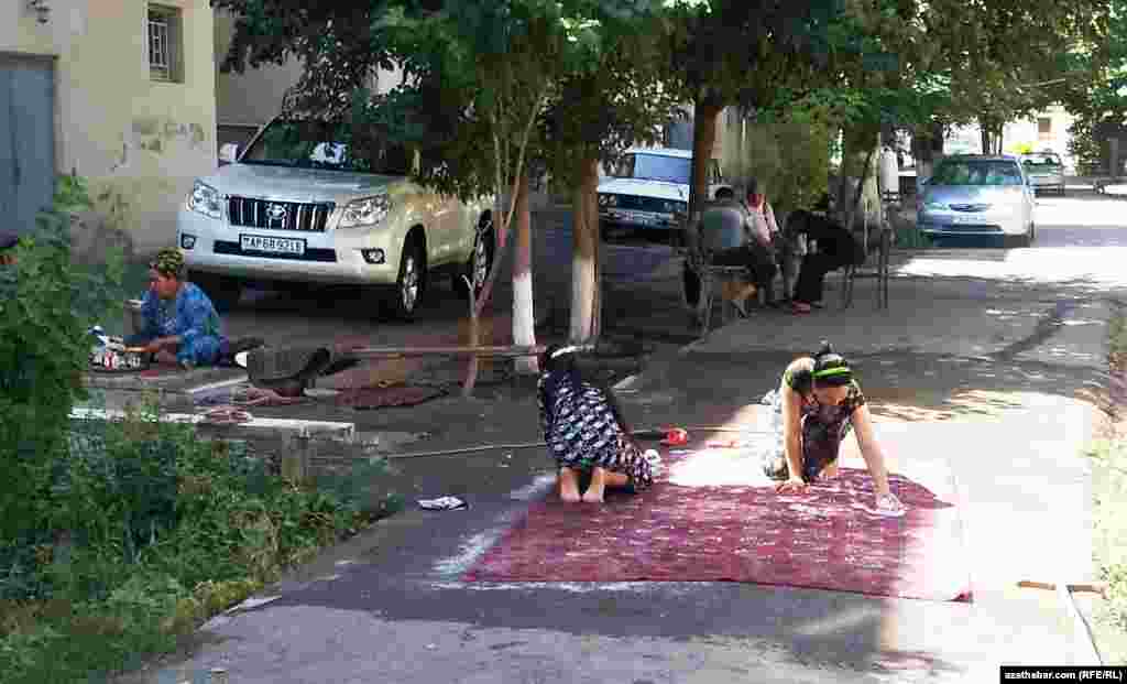 Gyzlar haly ýuwýar, olaryň ejeleri çaý içýär, kakalary hem sadranç oýnaýar.