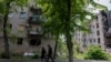 Чоловіки проходять повз пошкоджений житловий будинок у місті Лиман, поблизу лінії фронту в Донецькій області, 7 травня 2025 року