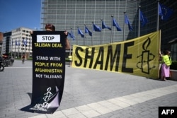 Активист Amnesty International держит плакат с надписью «Остановите сделку с Талибаном» у штаб-квартиры Европейской комиссии в Брюсселе, протестуя против встречи с делегацией «Талибана». 23 июня 2026 года