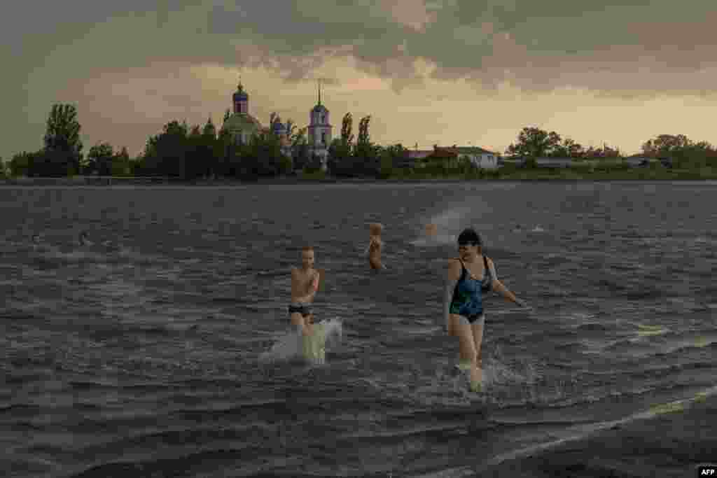 People swim in a lake on a hot summer day on the outskirts of Slovyansk in Ukraine's war-torn Donetsk region.