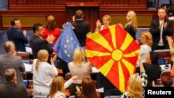 A kormányzó SDSM párt észak-macedón parlamenti képviselői európai uniós és észak-macedón zászlókkal a Bulgáriával fennálló viták rendezését és az uniós tagság felé vezető út megnyitását célzó, francia terv parlamenti vitája idején, 2022. július 16-án.