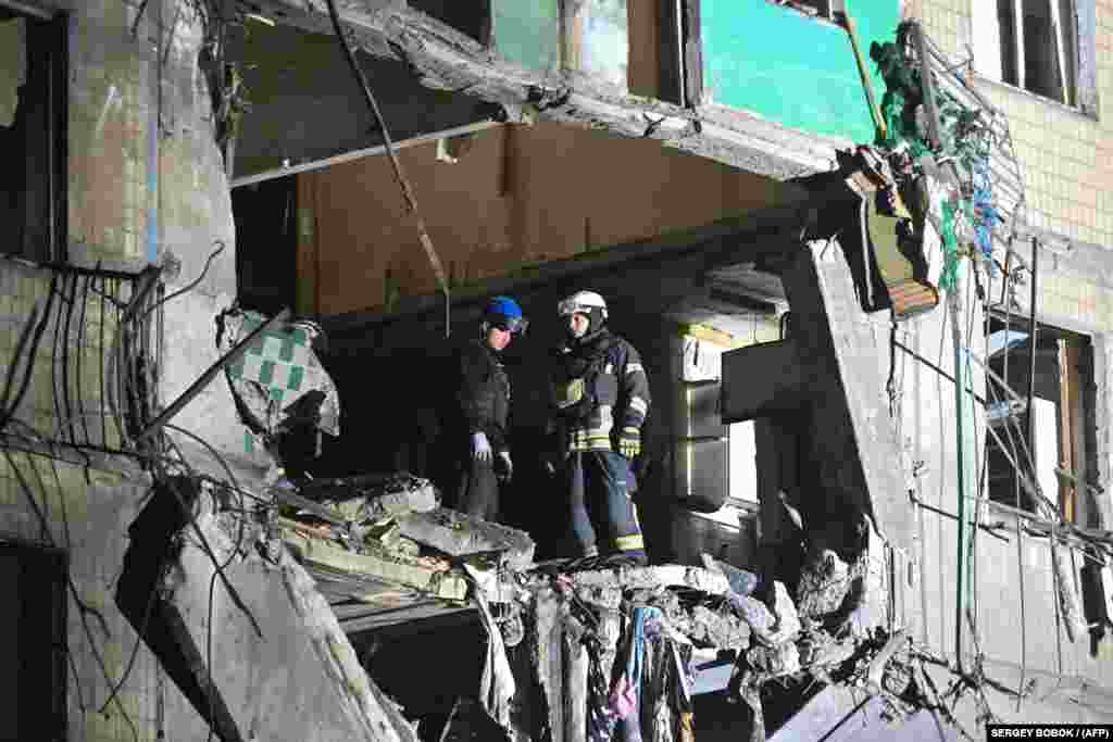 Ukrainian rescuers inspect damage to a residential building following a Russian missile attack in Kharkiv early on October 3.&nbsp;