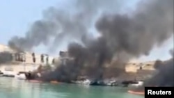 Smoke rises from boats on fire at a pier in Bushehr Province after a reported US projectile struck the area on July 9