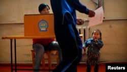 A child looks at a man as he votes at a polling station during the presidential election in Bayanchandmani on June 26.