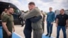 Ukrainian President Volodymyr Zelenskiy (left) smiles as the head of the Ukraine's presidential office, Andriy Yermak (center), hugs a defender of Mariupol's Azovstal steelworks before departing Istanbul international airport on July 8. 