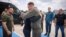 Ukrainian President Volodymyr Zelenskiy (left) smiles as the head of the Ukraine's presidential office, Andriy Yermak (center), hugs a defender of Mariupol's Azovstal steelworks before departing Istanbul international airport on July 8. 