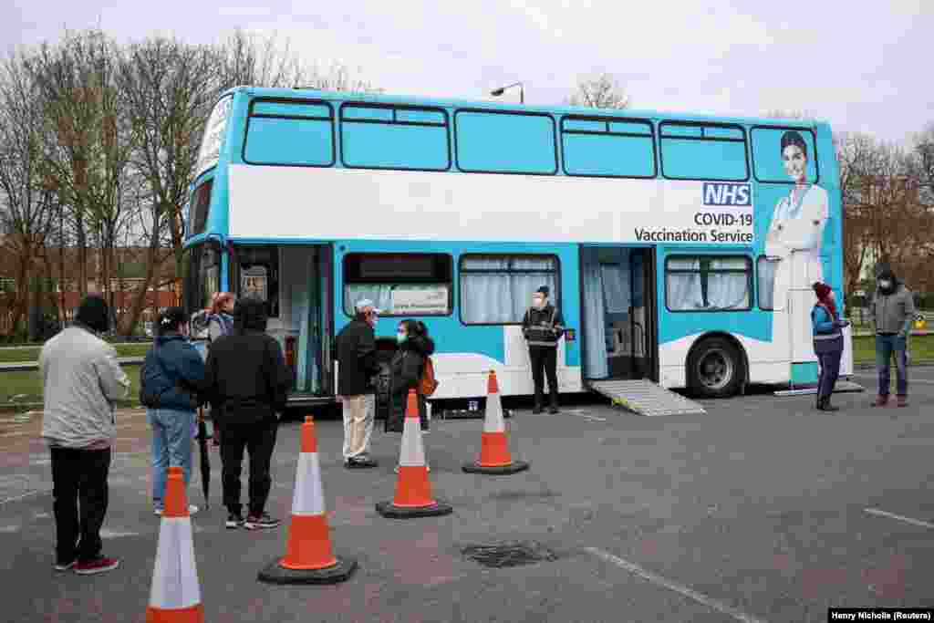 NË AUTOBUS - Njerëzit rreshtohen para një autobusi të shndërruar në qendër mobile vaksinimi për koronavirus, në Londër, Britani, më 14 shkurt 2021.