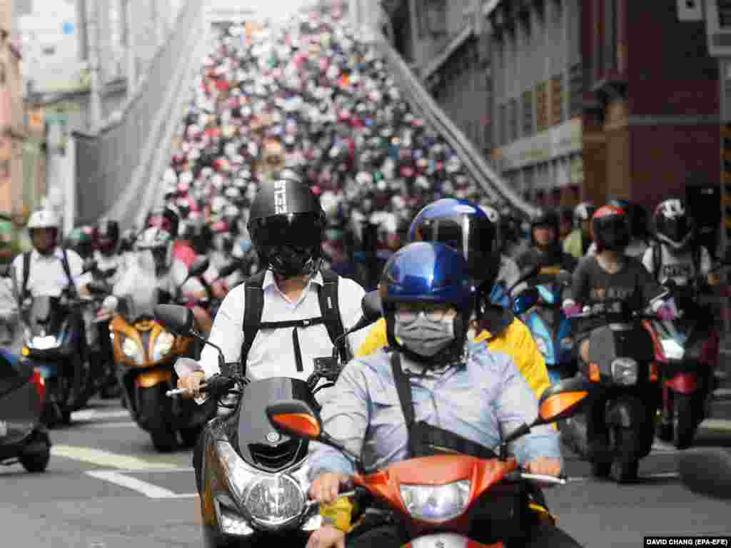 People riding scooters and motorcycles cross the Taipei Bridge from Sanchung to go to work in Taipei, Taiwan. The number of motorbikes moving down the Taipei Bridge has earned it the nickname Motorbike Waterfall, attracting many tourists and photographers every morning. Motorbikes are the most common means of transportation in Taiwan. According to the Environmental Protection Administration, there are nearly 14 million motorbikes in Taiwan, which has a population of 23 million. (EPA-EFE/David Chang)