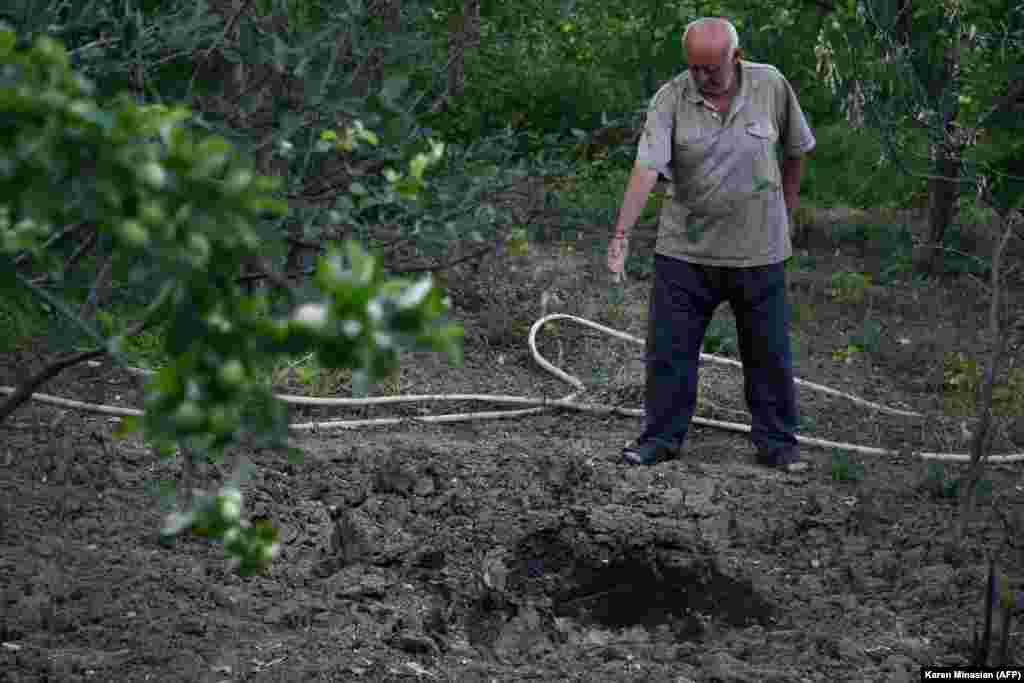 Чоловік вказує на кратер у землі. Це наслідок обстрілів під час боїв 15 липня у вірменському селі Айгепар
