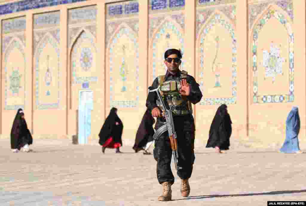 Afghan security forces stand guard as people arrive to offer Eid al-Adha prayers at a mosque in Herat, Afghanistan.