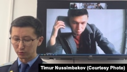 QazNews24 сатиралық паблигі авторы Темірлан Еңсебек (экранда) және прокурор Дидар Қабаев сот кезінде. Алматы, 9 сәуір, 2025 жыл.