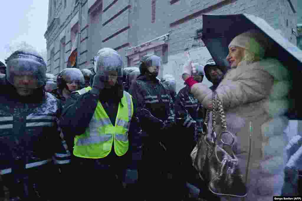 A woman takes pictures of policemen as they keep an eye on protesters attending a rally in support of arrested former Georgian President Mikheil Saakashvili outside a detention center in Kyiv. (AFP/Genya Savilov)