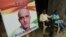 Residents sit next to a placard with a picture of Kulbhushan Sudhir Jadhav, an Indian national convicted of spying in Pakistan, in the neighborhood where he grew up, in Mumbai on July 17.