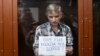 Moscow city deputy Aleksei Gorinov, who is accused of "distributing false information" about Russia's war in Ukraine, holds up a sign reading, "Do you need this war?" at his verdict hearing at a courthouse in Moscow on July 8.