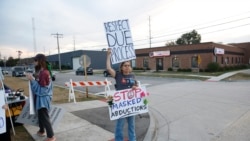 A protester holds signs outside an Immigration and Customs Enforcement (ICE) facility in Broadview, Illinois, on October 1