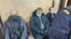 Uladzimer Kniha (left), Yauhen Raznichenka (center), and Dzmitry Furmanau appear in court in Hrodna on January 18.