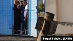 Locals in Stepanakert look the remains of a missile on a street after recent shelling on October 15. 