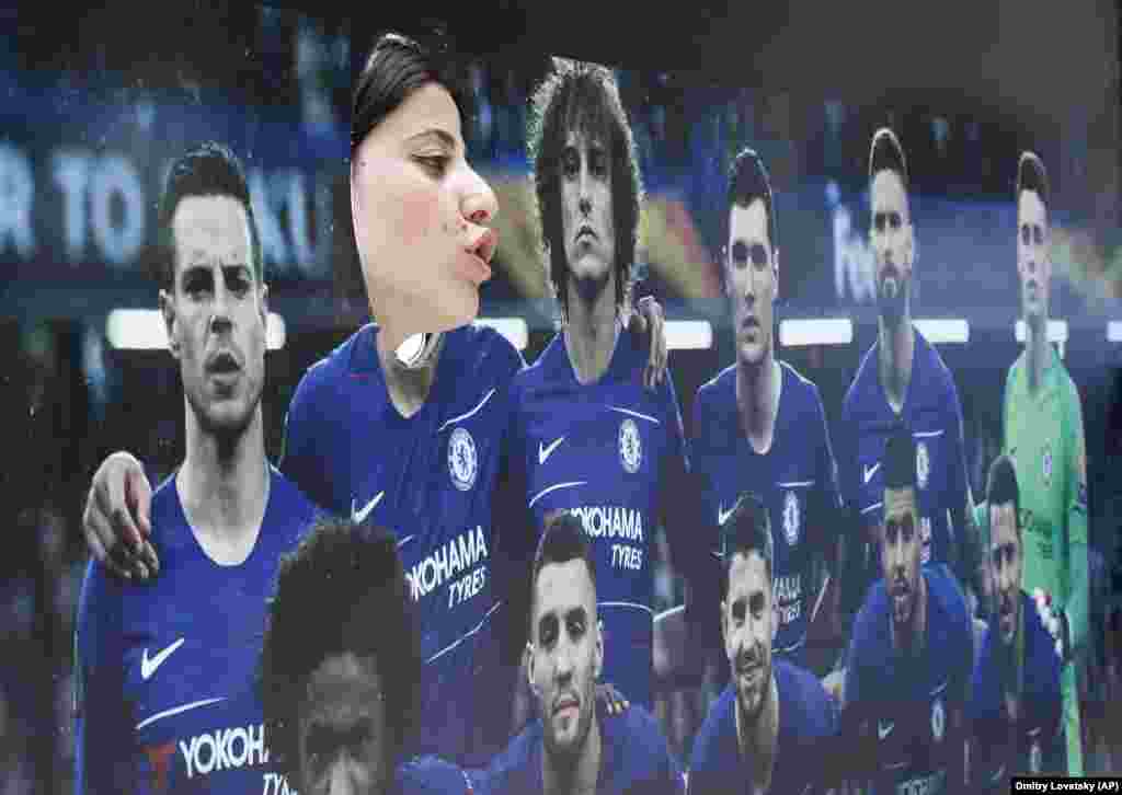 A woman poses with a poster of the Chelsea team in a fan zone on the eve of the Europa League final soccer match between Arsenal and Chelsea in Baku. (AP/Dmitri Lovetsky)