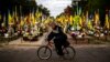 A man rides a bicycle past the graves of Ukrainian soldiers killed during the war, at Lisove cemetery in Kyiv. 