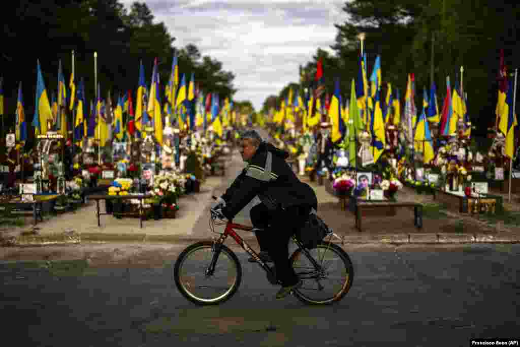 Човек вози велосипед покрај гробниците на украинските војници убиени за време на војната со Русија на гробиштата Лисове во Киев.