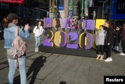 Ljudi se slikaju pored natpisa "Idi dalje, 2020!", na Times Squareu u New Yorku, 28. decembar, 2020.
