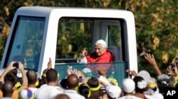 Benedict al XVI-lea salută mulțimea din papamobilul său, în timp ce sosește în Piața Revoluției din Havana, Cuba, 28 martie 2012.