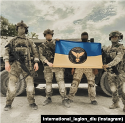 Бійці Міжнародного легіону при ГУР із прапором та символікою. Instagram/ international_legion_diu