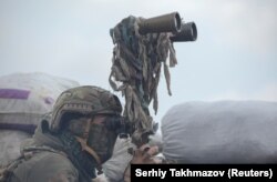 Военнослужащий украинских вооруженных сил в бинокль осматривает территорию на боевых позициях на линии разделения возле контролируемого повстанцами города Донецка, Украина, 6 апреля 2021 года.