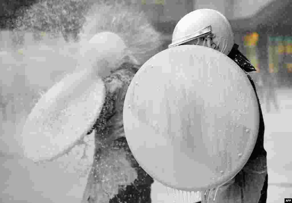 A police officer uses a shield to protect himself from milk being sprayed by dairy farmers during a protest against European Union agricultural policies in Brussels. Farmers demonstrated at the European Parliament with tractors and fake cows calling on political leaders to act on falling milk prices caused by overproduction in Europe. (AFP/John Thys)