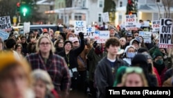 Люди тримають плакати, беручи участь у жалобній церемонії, Міннеаполіс, 7 січня 2026 року