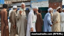 A man shows his ID card as he waits in line to vote in Pakistan's northwest on July 20.