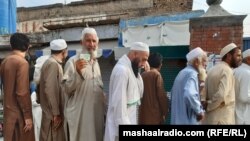 A man shows his ID card as he waits in line to vote in Pakistan's northwest on July 20.