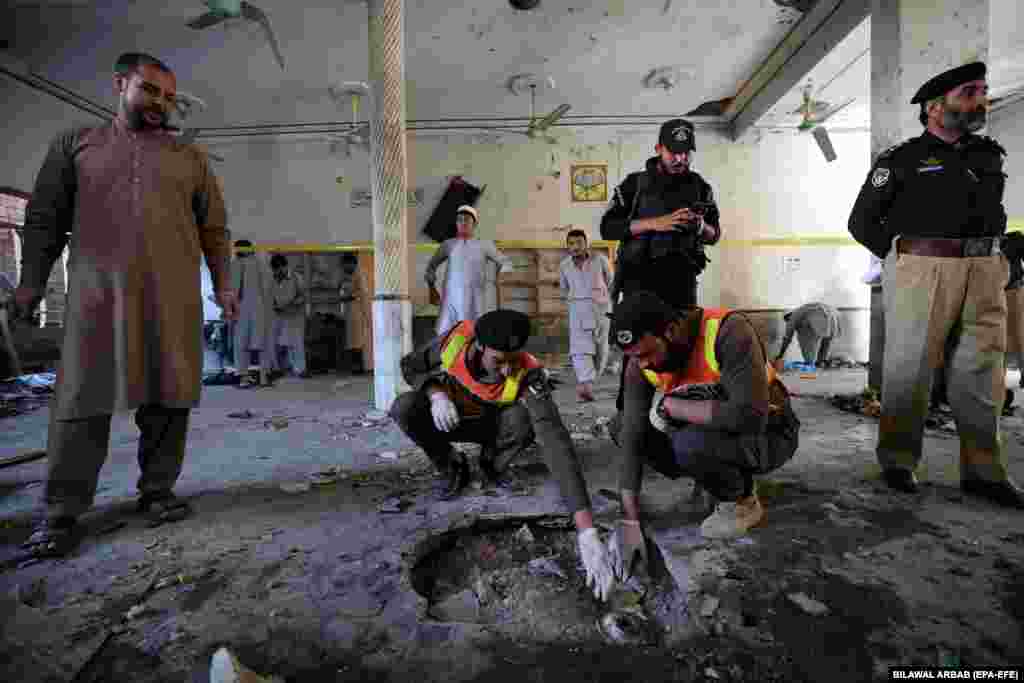 Pakistani security officials inspect the crater formed at the scene of the explosion.