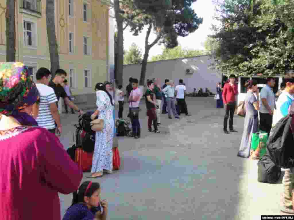 Aşgabat demirýol wokzalynyň öňündäki meýdançada ýolagçylar awtobusa garaşýarlar.