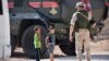 SYRIA -- Syrian children stand next to a member of the Russian military police in Jibrin, on the outskirts of Aleppo, August 16, 2017